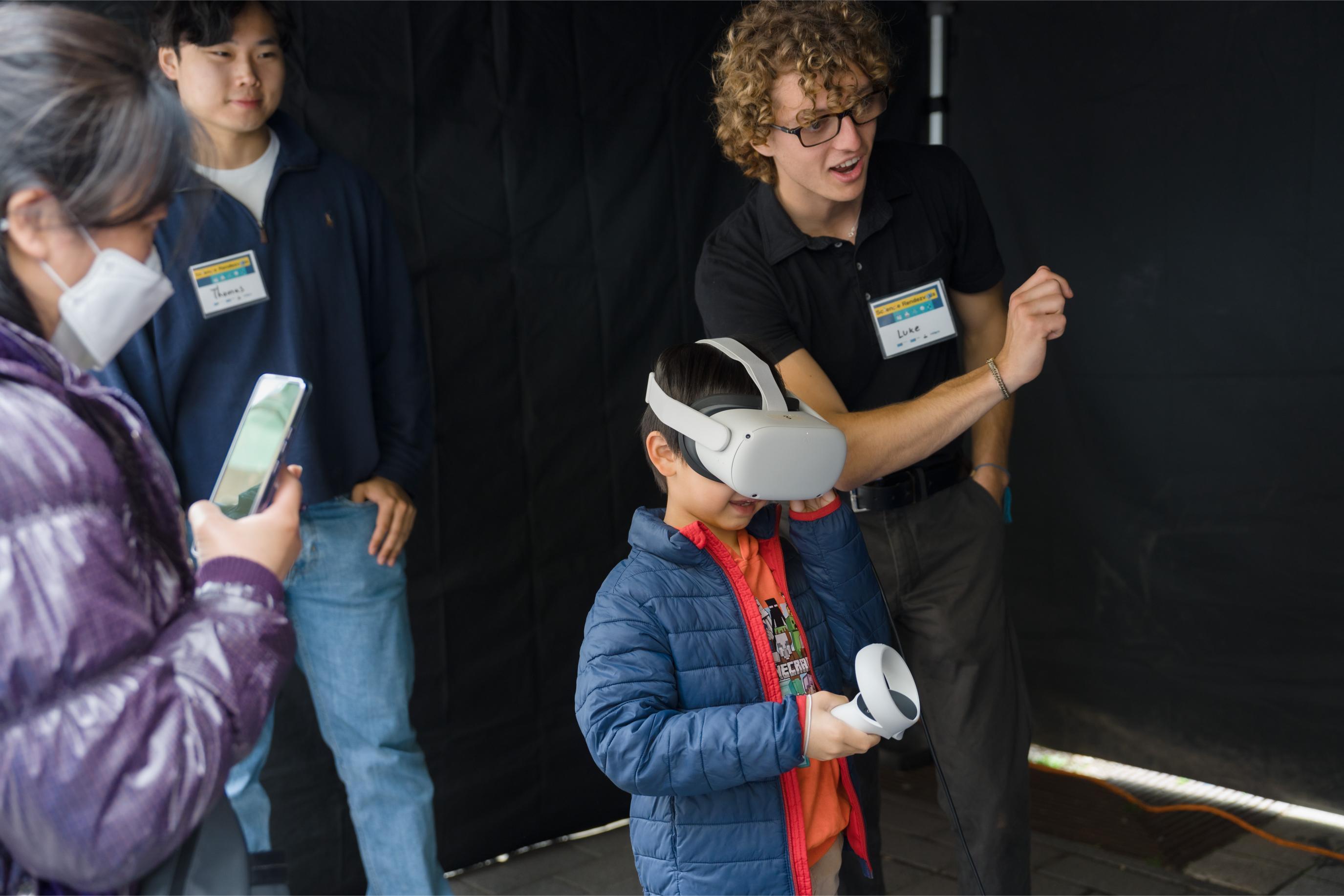A volunteer shows the young participant how to play the game at the Virtual Reality Games Booth.